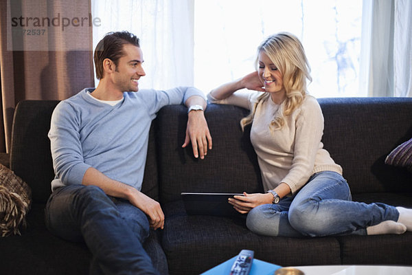Paar mit digitalem Tablett auf Sofa sitzend
