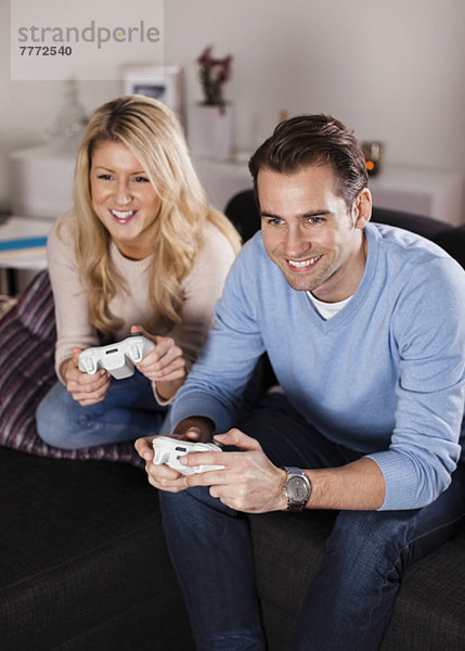 Glückliches Paar beim Spielen von Videospielen im Wohnzimmer