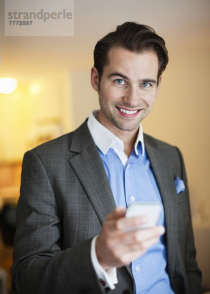 Porträt eines fröhlichen Mannes im Anzug mit Handy