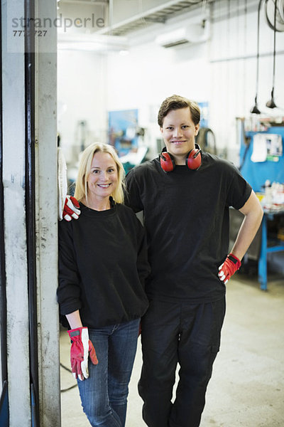 Porträt von selbstbewussten Mechanikern  die in der Kfz-Werkstatt zusammenstehen