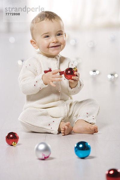 Kleiner Junge spielt mit Weihnachtsbällen