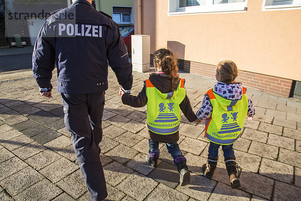 Polizist geht mit Grundschulkindern den Schulweg ab