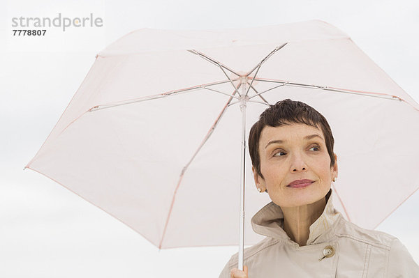 Regenmantel  Portrait  Frau  lächeln  Regenschirm  Schirm  halten  Kleidung