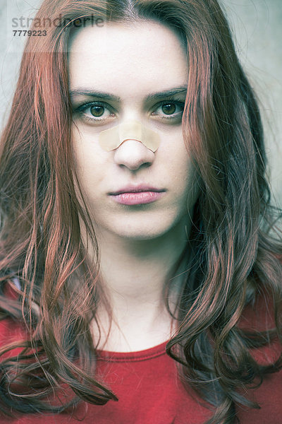 Porträt einer jungen Frau mit einem Pflaster auf der Nase