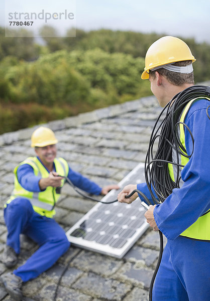 Arbeiter installieren Solarpanel auf dem Dach