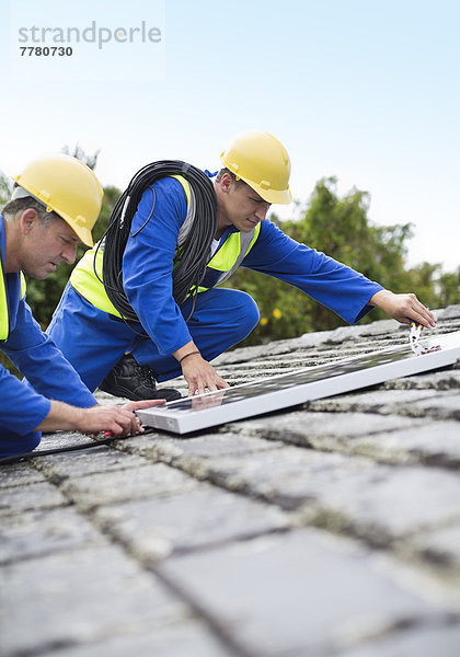 Arbeiter installieren Solarmodule auf dem Dach