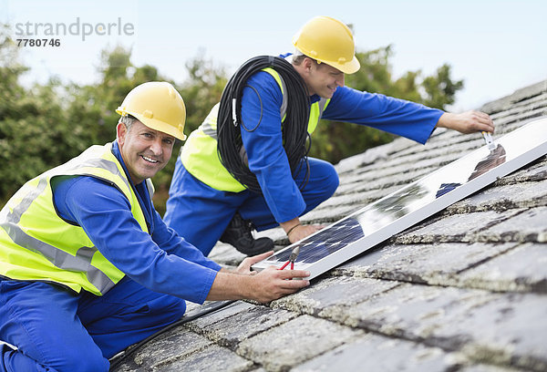 Arbeiter installieren Solarmodule auf dem Dach