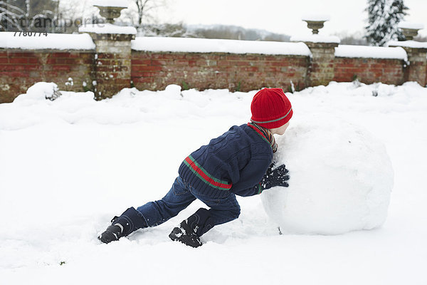 Junge macht Schneemann im Freien