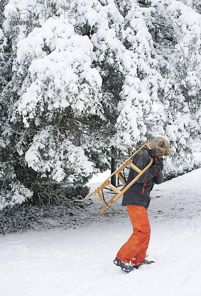 Junge mit Holzschlitten im Schnee