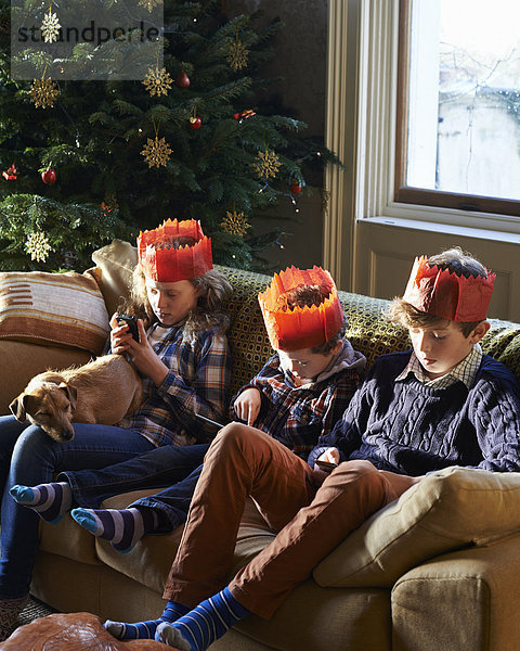 Kinder in Papierkronen entspannen auf dem Sofa