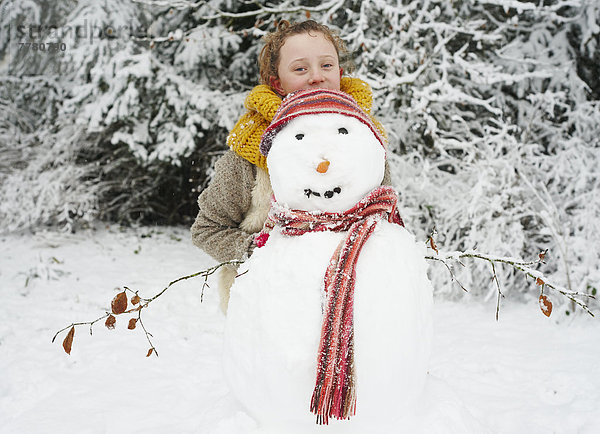 Mädchen macht Schneemann im Freien