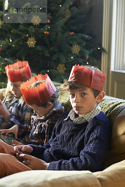 Kinder in Papierkronen entspannen auf dem Sofa