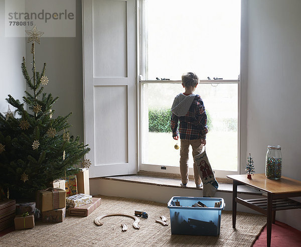 Junge mit Weihnachtsstrumpf am Fenster