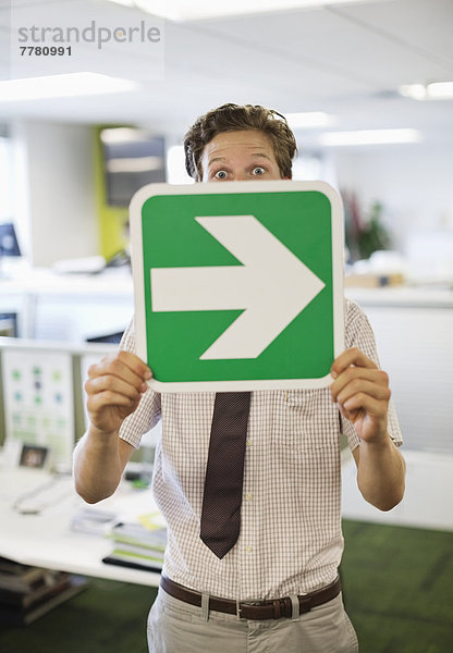 Geschäftsmann mit Pfeilschild im Amt