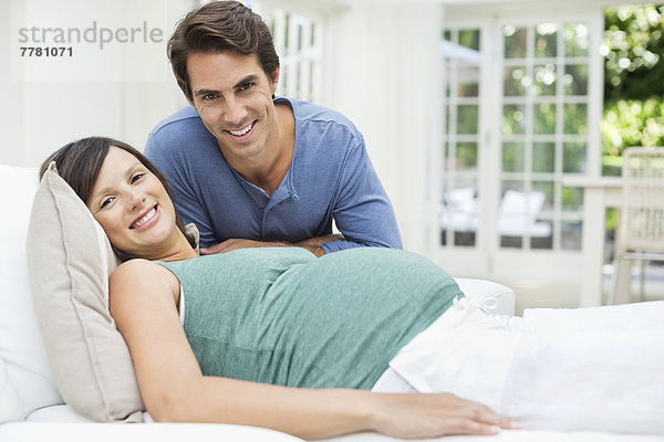 Mann neben schwangerer Frau auf dem Bett sitzend