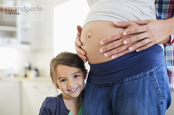 Mädchen lächelt mit schwangeren Mutterbauch