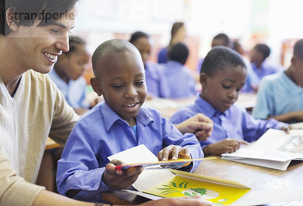 Lehrer  der mit dem Schüler im Klassenzimmer arbeitet