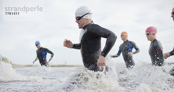 Triathleten in Trikots  die in Wellen laufen