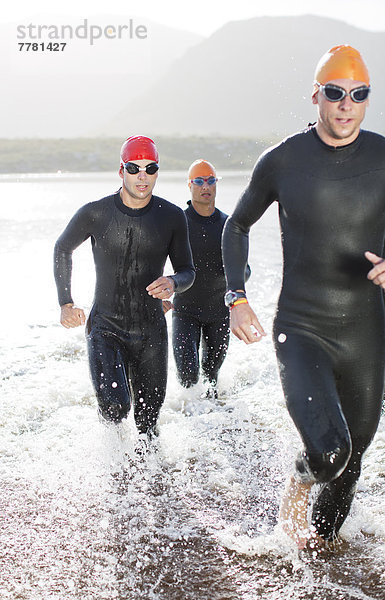 Triathleten in Trikots  die in Wellen laufen