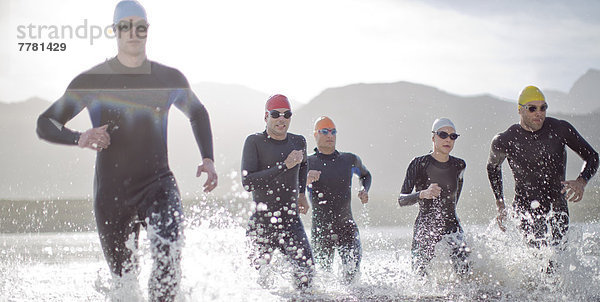 Triathleten in Trikots  die in Wellen laufen