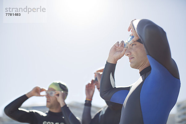 Triathletinnen und Triathleten  die ihre Brille im Freien anpassen