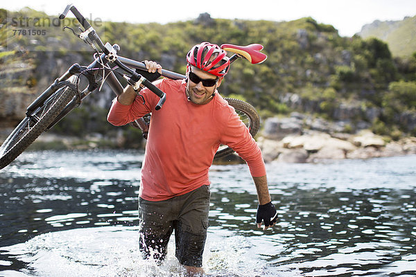 Mann mit Mountainbike im Fluss