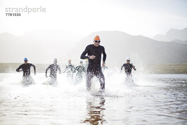 Triathleten  die aus dem Wasser auftauchen