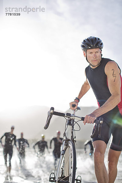 Mann schiebt Fahrrad am Strand