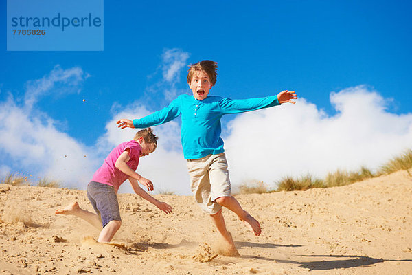 Zwei Jungen rennen die Sanddüne hinunter.