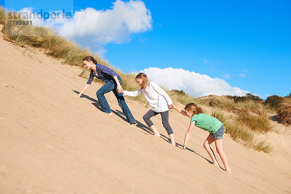 Drei Mädchen klettern auf die Sanddüne