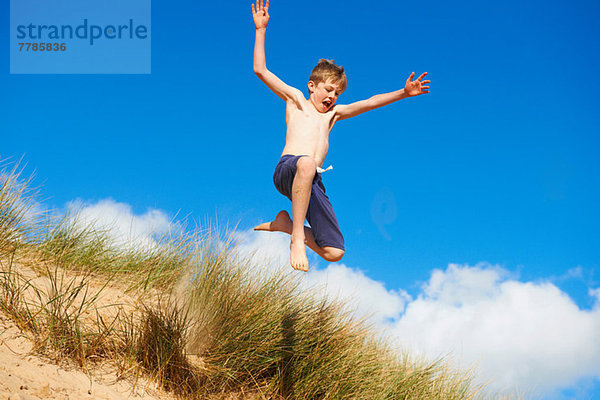 Junge springt am Strand