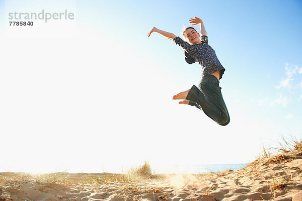 Teenager-Mädchen beim Springen am Strand