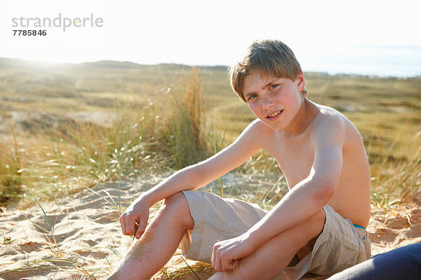 Junge sitzt am Strand