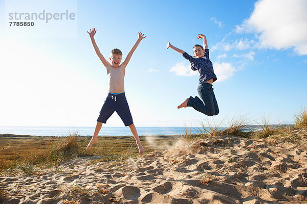 Junge und junges Mädchen springen am Strand