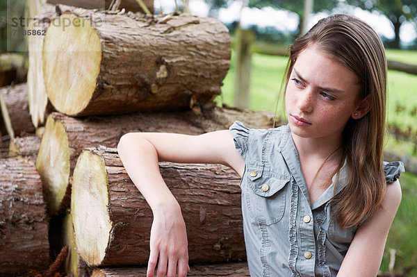 Teenager-Mädchen  das sich im Wald auf Baumstämme stützt.