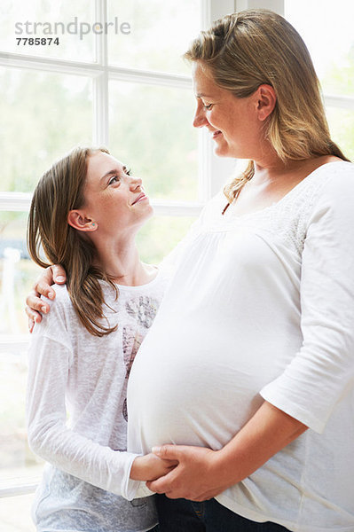 Schwangere Mutter mit jugendlicher Tochter am Fenster