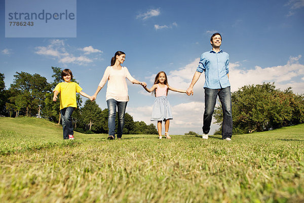 Familie mit zwei Kindern beim Händchenhalten  Spazierengehen