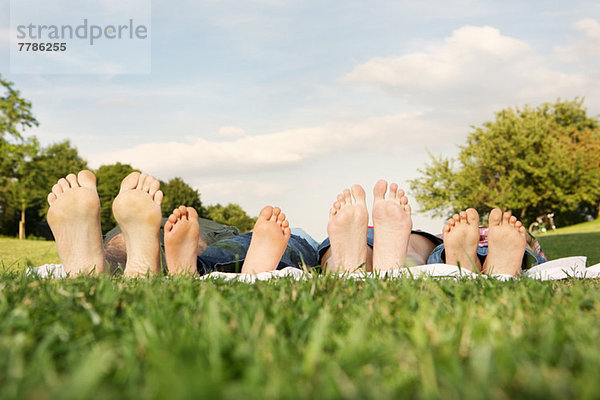 Familie mit zwei Kindern auf Gras liegend  Schwerpunkt Füße