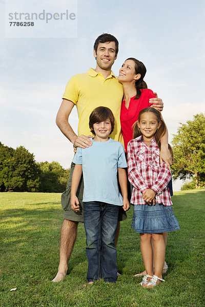 Porträt einer Familie mit zwei Kindern auf Rasen stehend