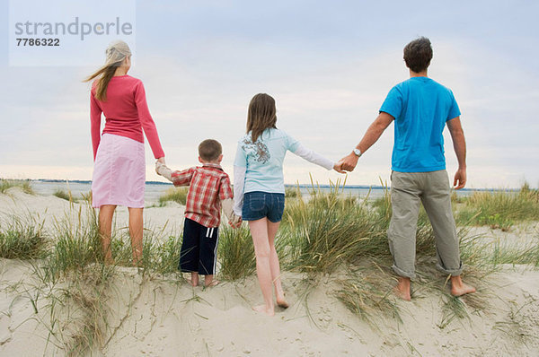 Familie hält sich am Strand an den Händen