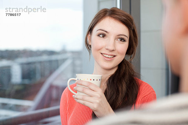 Junge Frau mit Kaffeetasse am Fenster