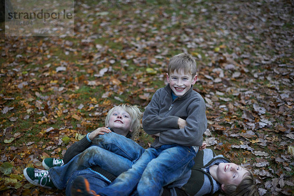 Jungen spielen Kämpfe auf dem Waldboden.