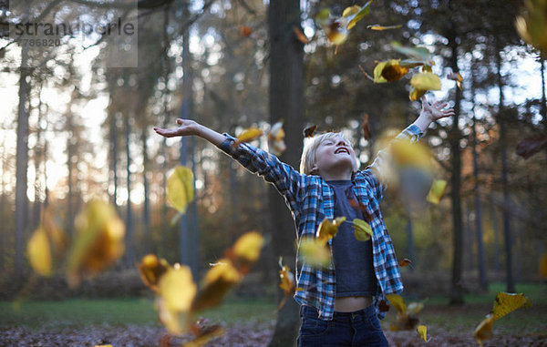 Junge wirft Blätter in die Luft