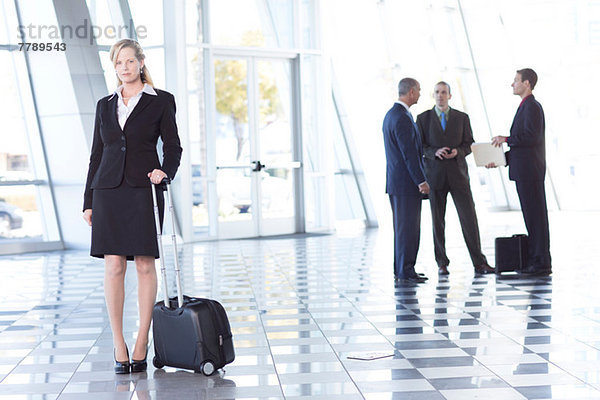 Portrait der Geschäftsfrau im Flughafen mit Koffer