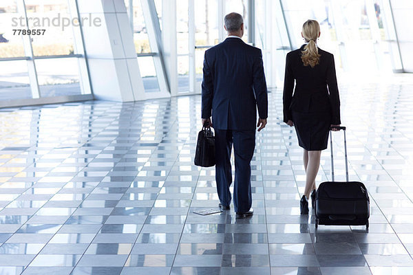 Geschäftsleute  die mit Koffern durch den Flughafen laufen