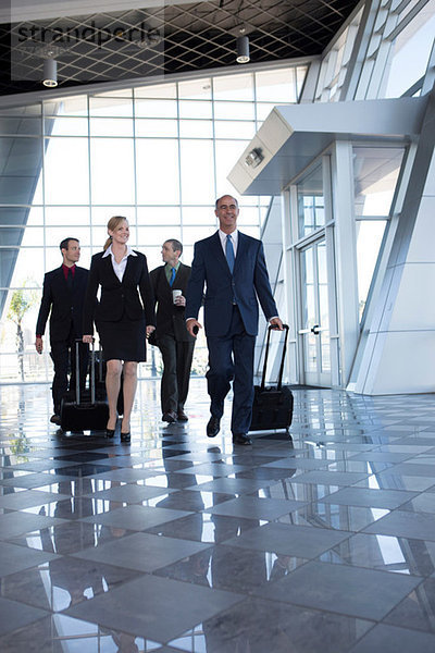 Geschäftsleute  die mit Koffern durch den Flughafen laufen