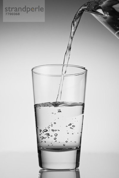 Wasser wird in Trinkglas gegossen