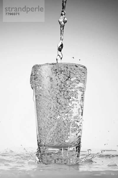Wasser  das in Trinkglas gegossen wird und überläuft