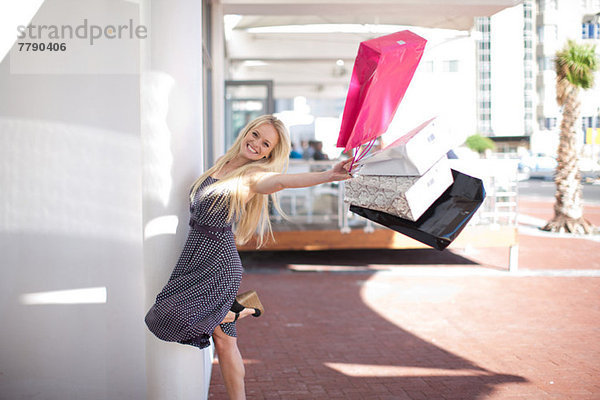 Eine glückliche junge Frau schwingt Einkaufstaschen.