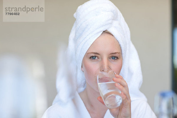 Junge Frau mit Handtuch auf dem Kopf Trinkwasser
